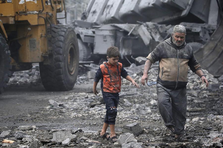 Varios palestinos caminan entre los escombros de un edificio destruido por Israel, en la población de Deir al Balah, en el sur de la Franja de Gaza. EFE/EPA/Mohammed Saber