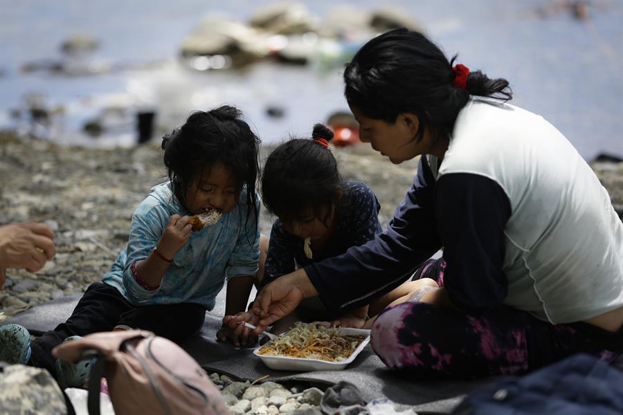 Una migrante ecuatoriana come junto a sus hijas en la selva mientras esperan para ser trasladados en canoa desde la Quebrada León hasta a la comunidad de Bajo Chiquito en Darién (Panamá), en una fotografía de archivo. EFE/ Bienvenido Velasco