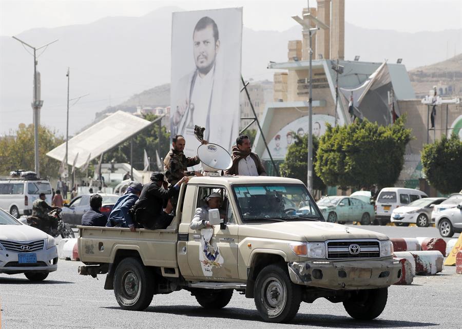 Simpatizantes hutíes viajan en un vehículo pasando junto a una pancarta que representa al máximo líder hutí, Abdul-Malik al-Houthi, en una fotografía de archivo. EFE/EPA/Yahya Arhab