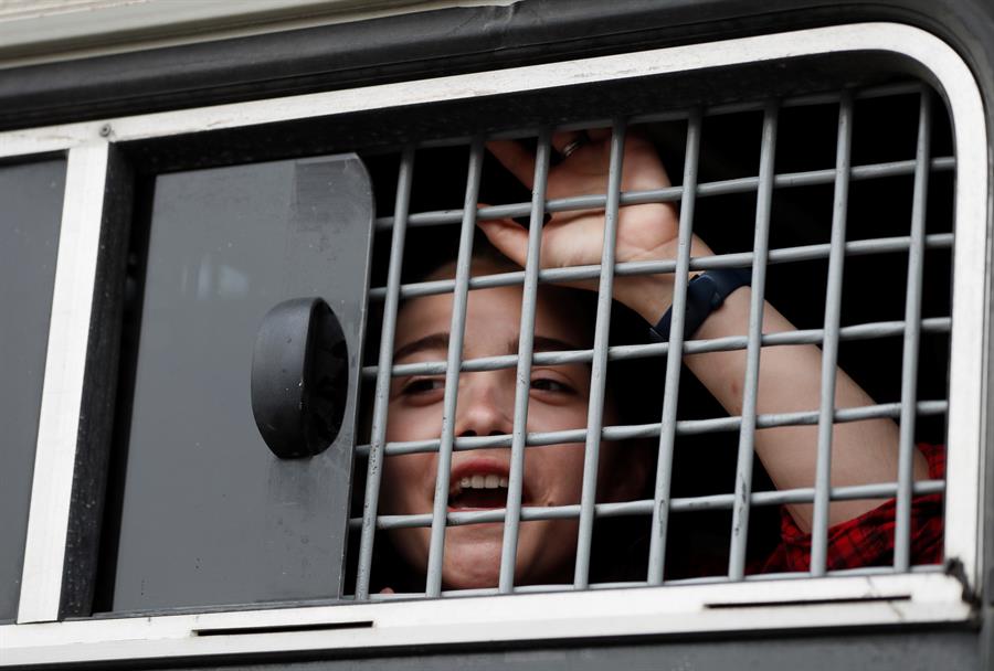 Foto archivo. Una mujer detenida por la Guardia Nacional rusa observa desde la ventana de un vehículo durante una manifestación en apoyo a periodista ruso detenido. EFE/ Yuri Kochetkov