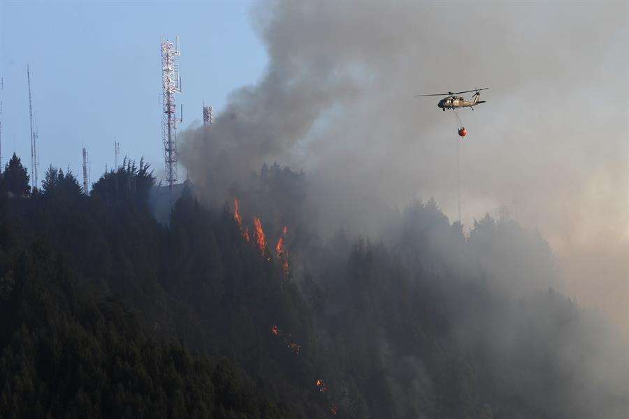 Un helicóptero combate hoy un incendio forestal en el cerro El Cable, en Bogotá (Colombia). EFE/ Carlos Ortega