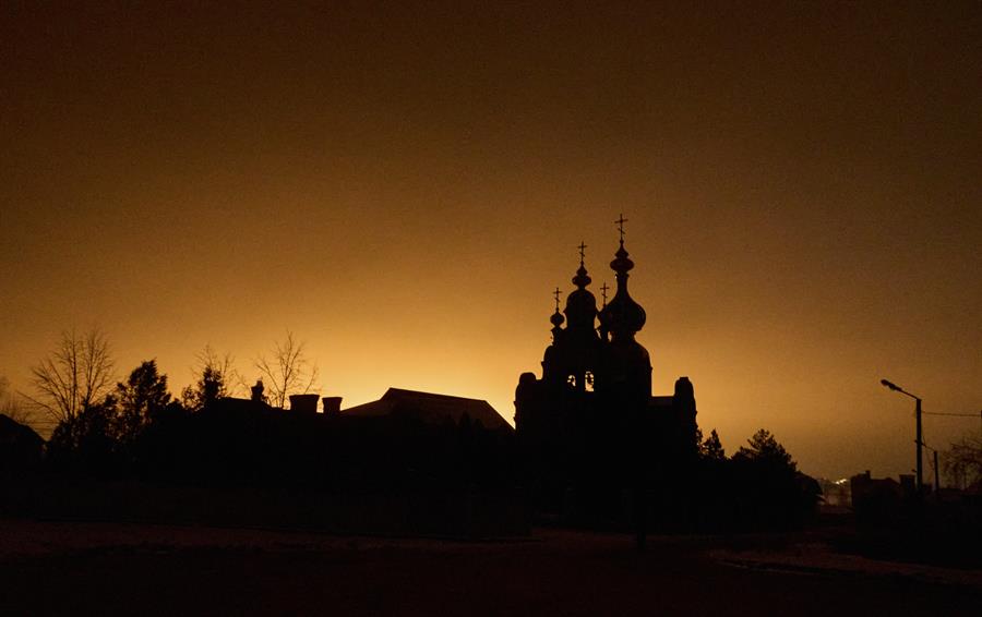 Foto archivo. Una iglesia se ve iluminada por el fuego causado por un ataque aéreo ruso en un bloque de viviendas en Járkov. EFE/Sergey Kozlov