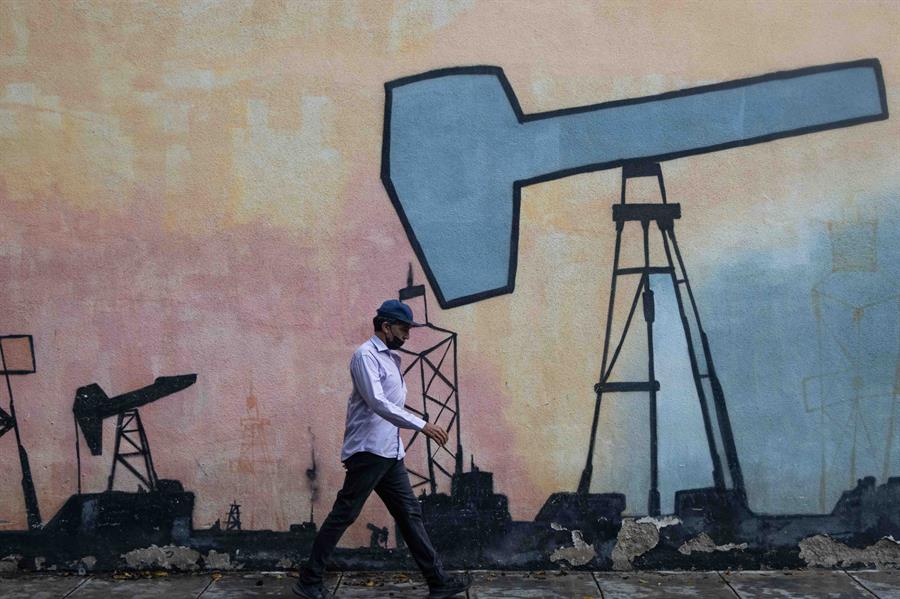 Un hombre pasa frente a un mural que muestra el proceso de extracción de petróleo frente a una sede de la estatal Petróleos de Venezuela S.A (Pdvsa), en una foto de archivo. EFE/ Ronald Peña