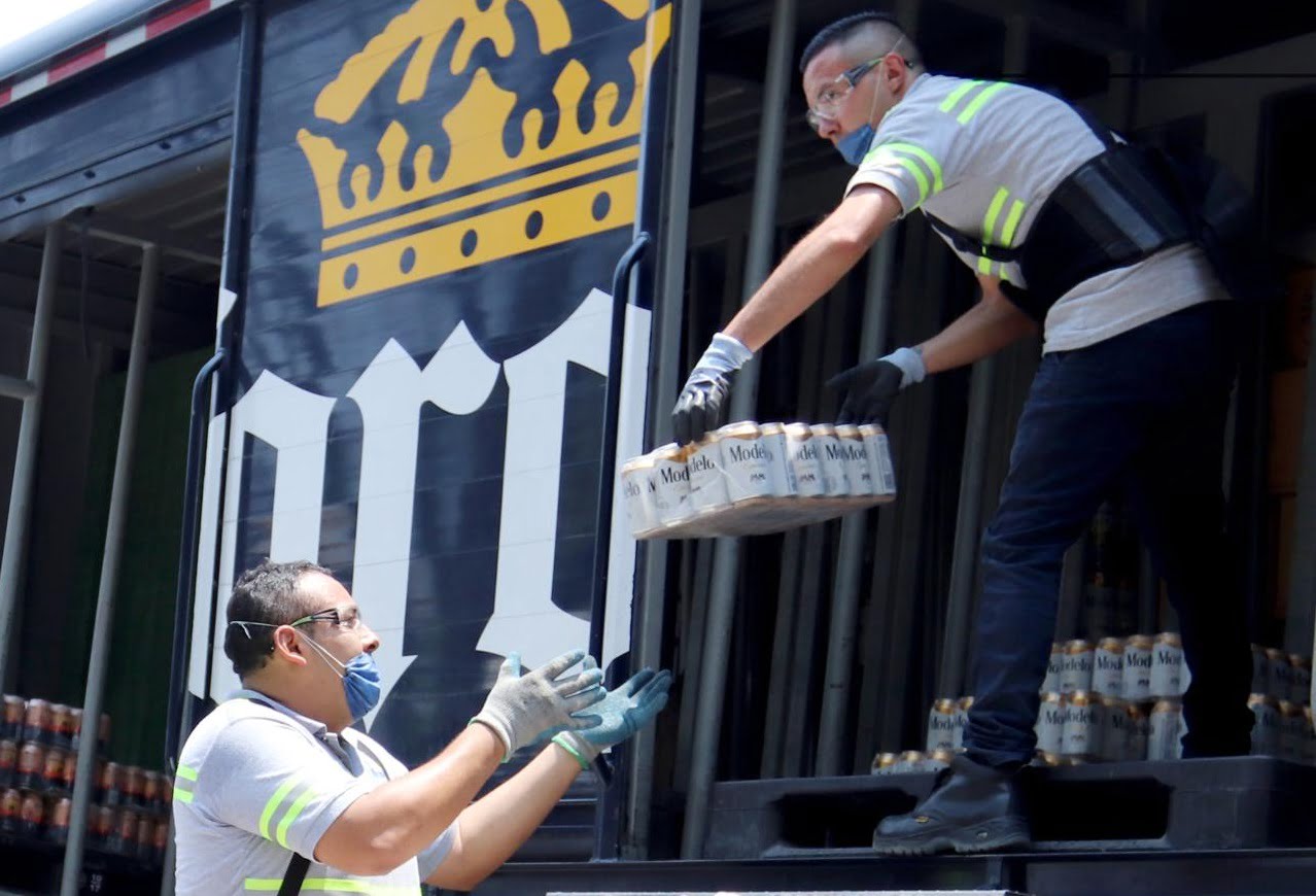 Unos trabajadores de la empresa mexicana Grupo Modelo trasladan paquetes de cervezas para su venta en tiendas de la Ciudad de México (México). EFE/José Pazos