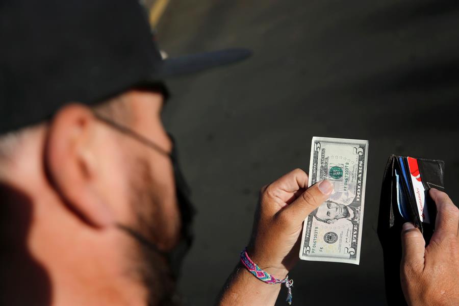 Una persona guarda en su billetera un billete de 5 dólares en Tepatitlán, Jalisco (México). EFE/ Francisco Guasco