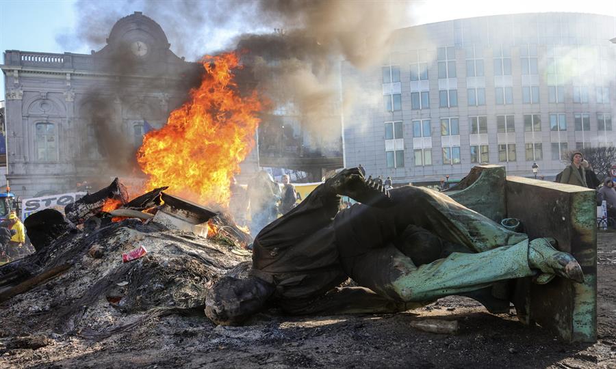 Una estatua yace en el suelo mientras arde un fuego durante una protesta de agricultores frente al Parlamento Europeo al margen de una cumbre de la UE en Bruselas, Bélgica, el 1 de febrero de 2024. EFE/EPA/Olivier Matthys
