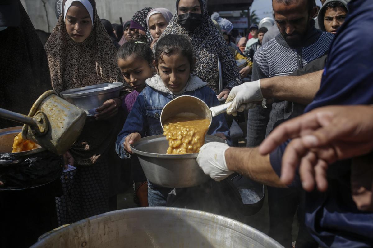 Niños palestinos desplazados reciben alimentos proporcionados por donantes árabes y palestinos en la ciudad de Deir al Balah, al sur de la Franja de Gaza, el 24 de febrero de 2024. EFE/MOHAMMED SABER