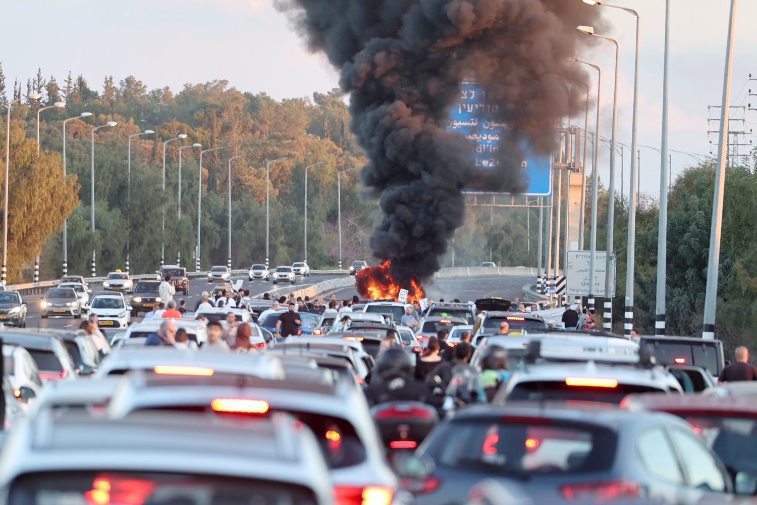 Los automovilistas esperan atascados mientras familiares de rehenes israelíes retenidos por Hamas en Gaza encienden un fuego y bloquean la carretera principal que va de Tel Aviv a Jerusalén, durante una protesta exigiendo su liberación, cerca del aeropuerto Ben Gurion, Israel, el 8 de marzo de 2024. EFE/ABIR SULTAN