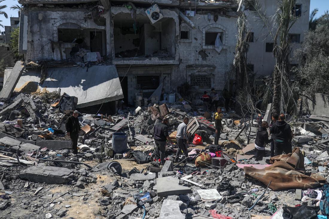 Palestinos rescatan algunas pertenencias y buscan personas desaparecidas entre los escombros de una casa destruida tras un ataque aéreo israelí en la ciudad de Deir Al Balah, al sur de la Franja de Gaza, el 13 de marzo de 2024. EFE/EPA/MOHAMMED SABLE