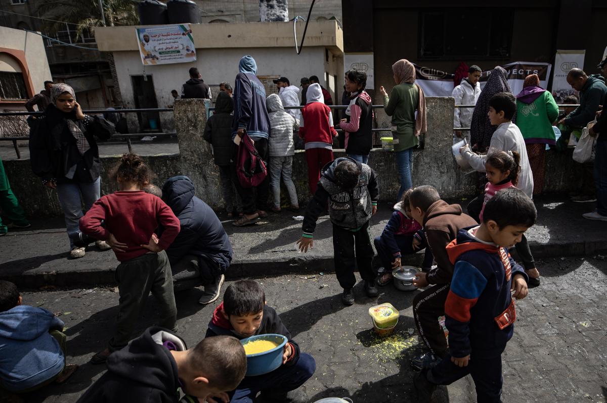 Niños palestinos desplazados se reúnen para comer la ayuda alimentaria proporcionada por un grupo de jóvenes palestinos en el campo de refugiados de Rafah, en el sur de la Franja de Gaza, el 7 de marzo de 2024. EFE/EPA/HAITHAM IMAD