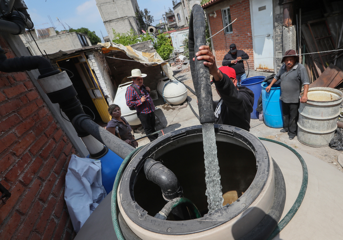 Un hombre llena unos tanques con agua en Santa María Aztahuacan, en la Ciudad de México (México). EFE/Mario Guzmán