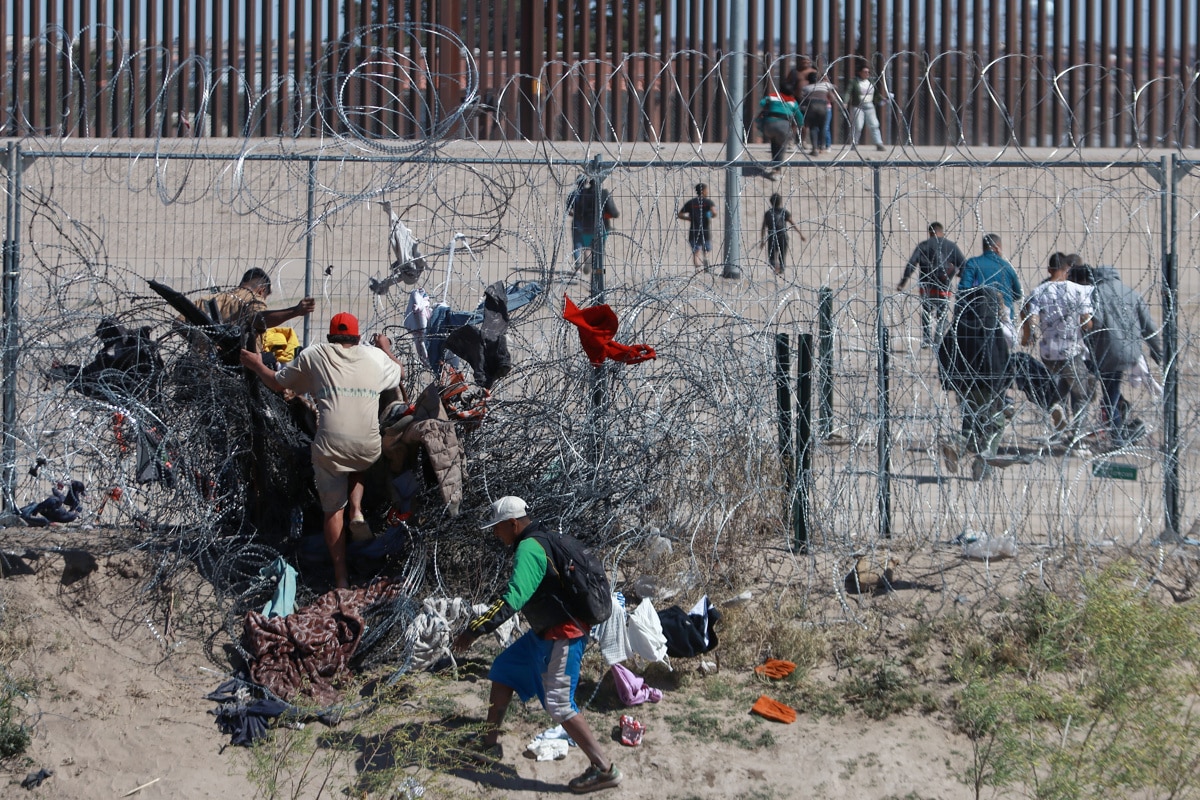 Migrantes cruzan una alambrada de navajas y púas, en la frontera que divide a México de los Estados Unidos en Ciudad Juárez (México). EFE/Luis Torres