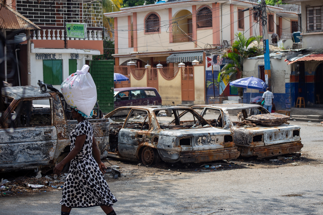Foto de archivo de transeúntes caminando frente a los restos de vehículos incendiados en el centro de Puerto Príncipe (Haití). EFE/ Mentor David Lorens