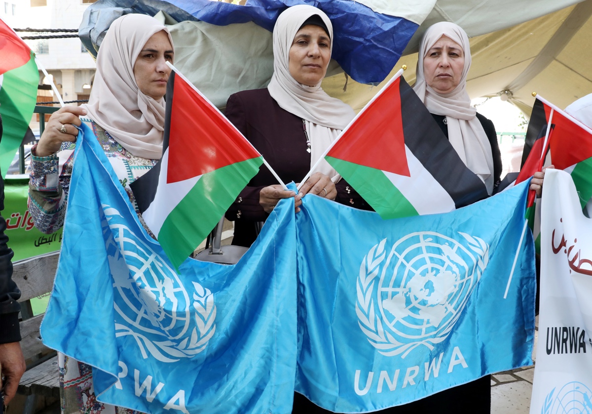 Fotografía de archivo de refugiados y activistas palestinas que sostienen banderas de la agencia de las Naciones Unidas para los refugiados palestinos (UNRWA) en Hberon. EFE/EPA/Abed Al Hashlamoun