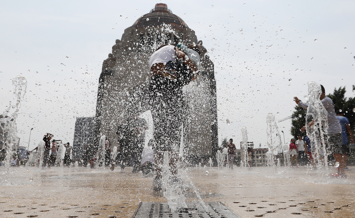 Personas se refrescan en una fuente del Monumento a la Revolución, en la Ciudad de México (México). Imagen de archivo. EFE/ Mario Guzmán