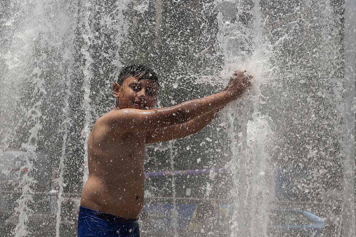 Un niño se baña en una fuente pública, debido a las altas temperaturas registradas en la Ciudad de México (México). EFE/José Méndez