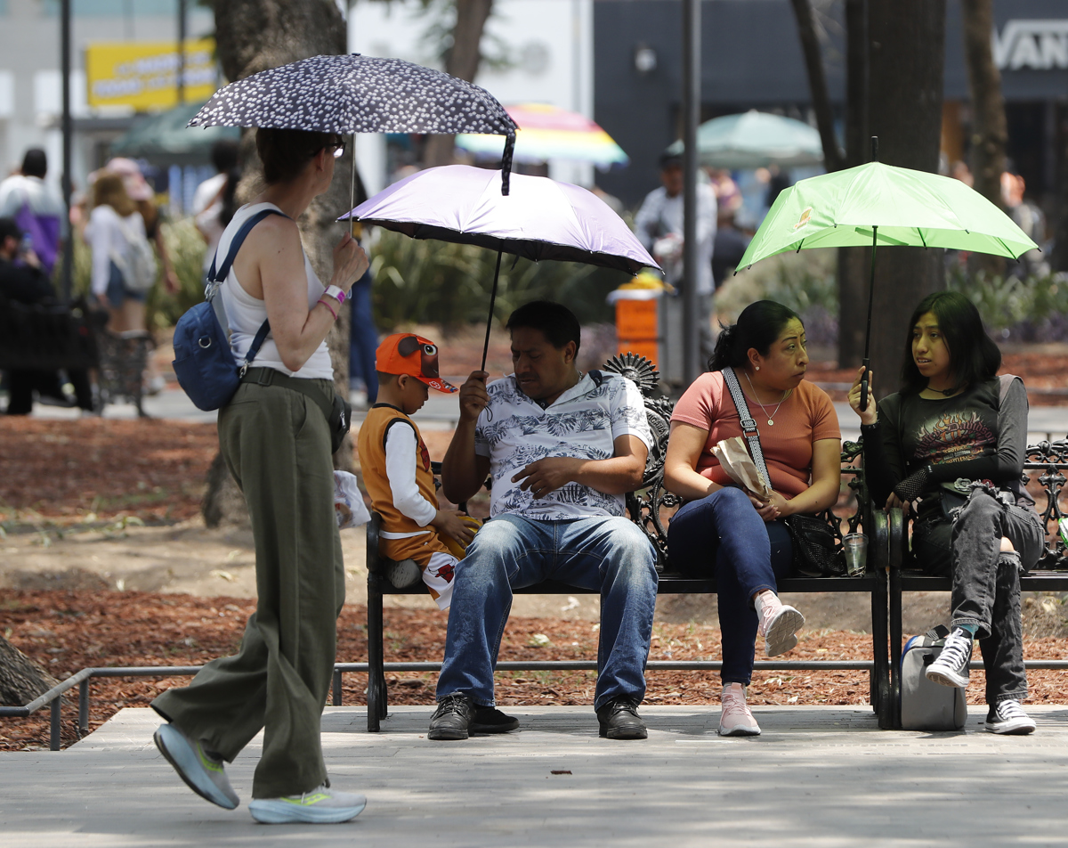 Personas se protegen del sol con sombrillas en el parque de la Alameda Central en la Ciudad de México (México). Imagen de archivo. EFE/Mario Guzmán