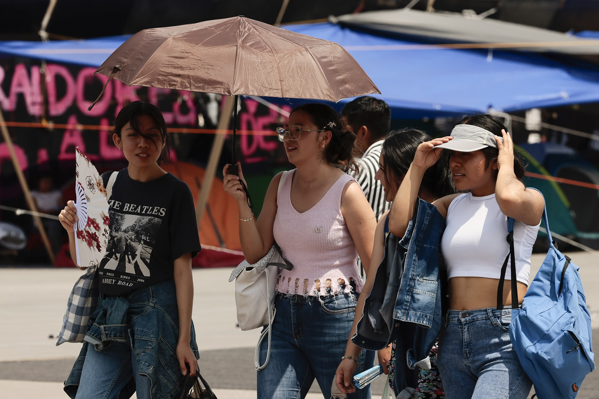 Varias personas caminan con sombrilla para protegerse del sol en Ciudad de México (México). EFE/José Méndez