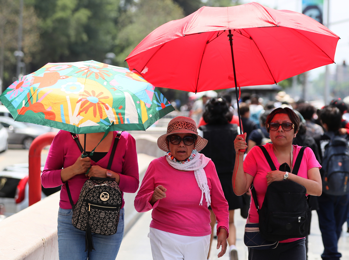 Mujeres sostienen sombrillas para protegerse del sol en la Ciudad de México (México). EFE/Mario Guzmán