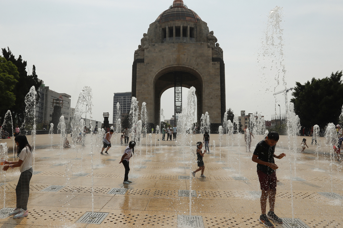 Personas juegan en una fuente del Monumento a la Revolución este domingo, en la Ciudad de México (México). EFE/ Mario Guzmán
