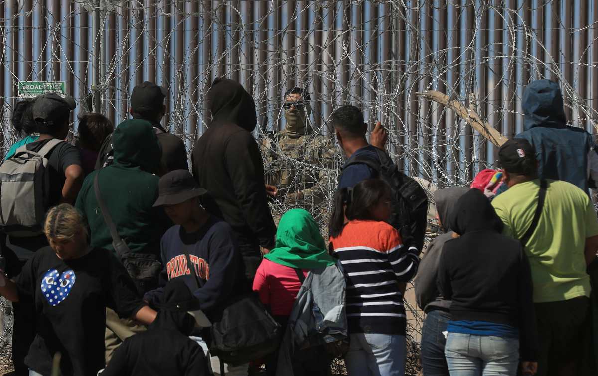 Migrantes esperan entre los alambres de púas mientras un agente estadounidense vigila en Ciudad Juárez, Chihuahua (México). EFE/Luis Torres