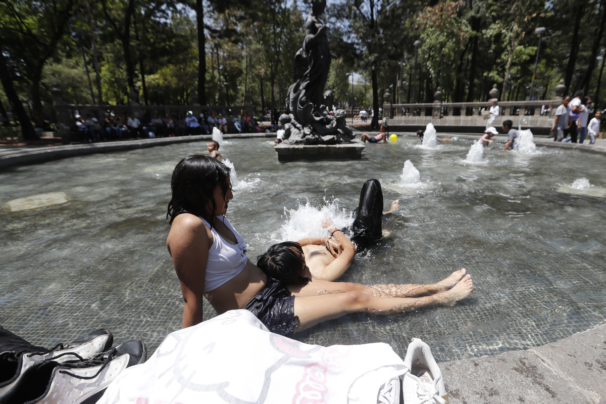 Jóvenes se refrescan en una fuente en la Ciudad de México (México). EFE/ Mario Guzmán