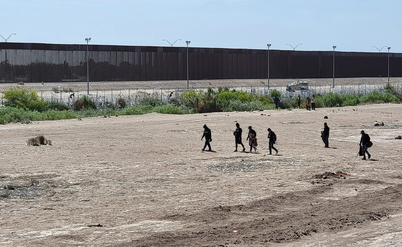 Foto de archivo de migrantes caminando por una orilla de la línea divisoria entre México y Estados Unidos, en Ciudad Juárez, en el estado de Chihuahua (México). EFE/ Luis Torres