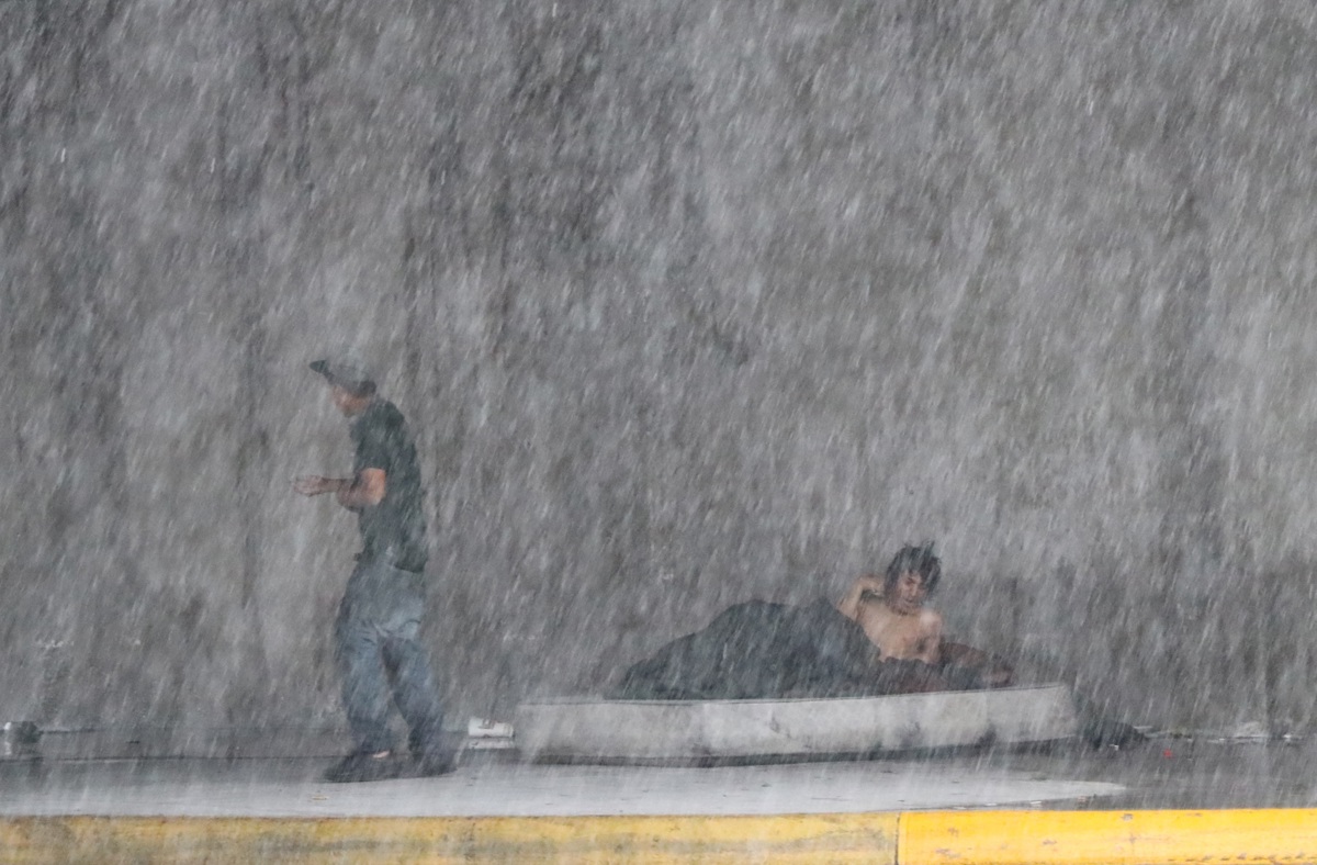 Dos habitantes de calle se protegen de la lluvia en una avenida de Monterrey (México). Fotografía de archivo. EFE/ María Julia Castañeda