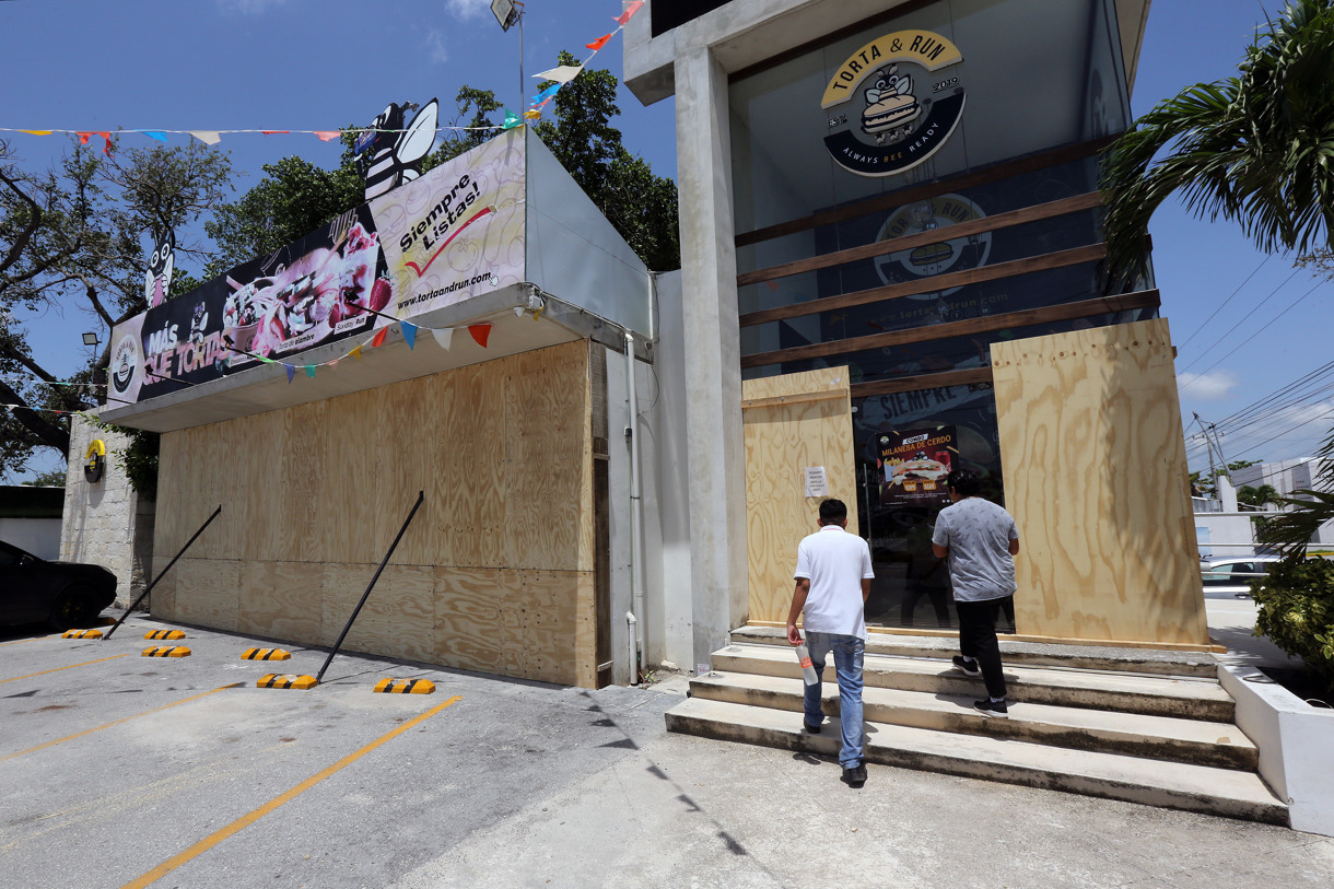 Trabajadores colocan tablas de madera para proteger un establecimiento por el paso del huracán Beryl, este miércoles en Cancún (México). (EFE/Alonso Cupul)