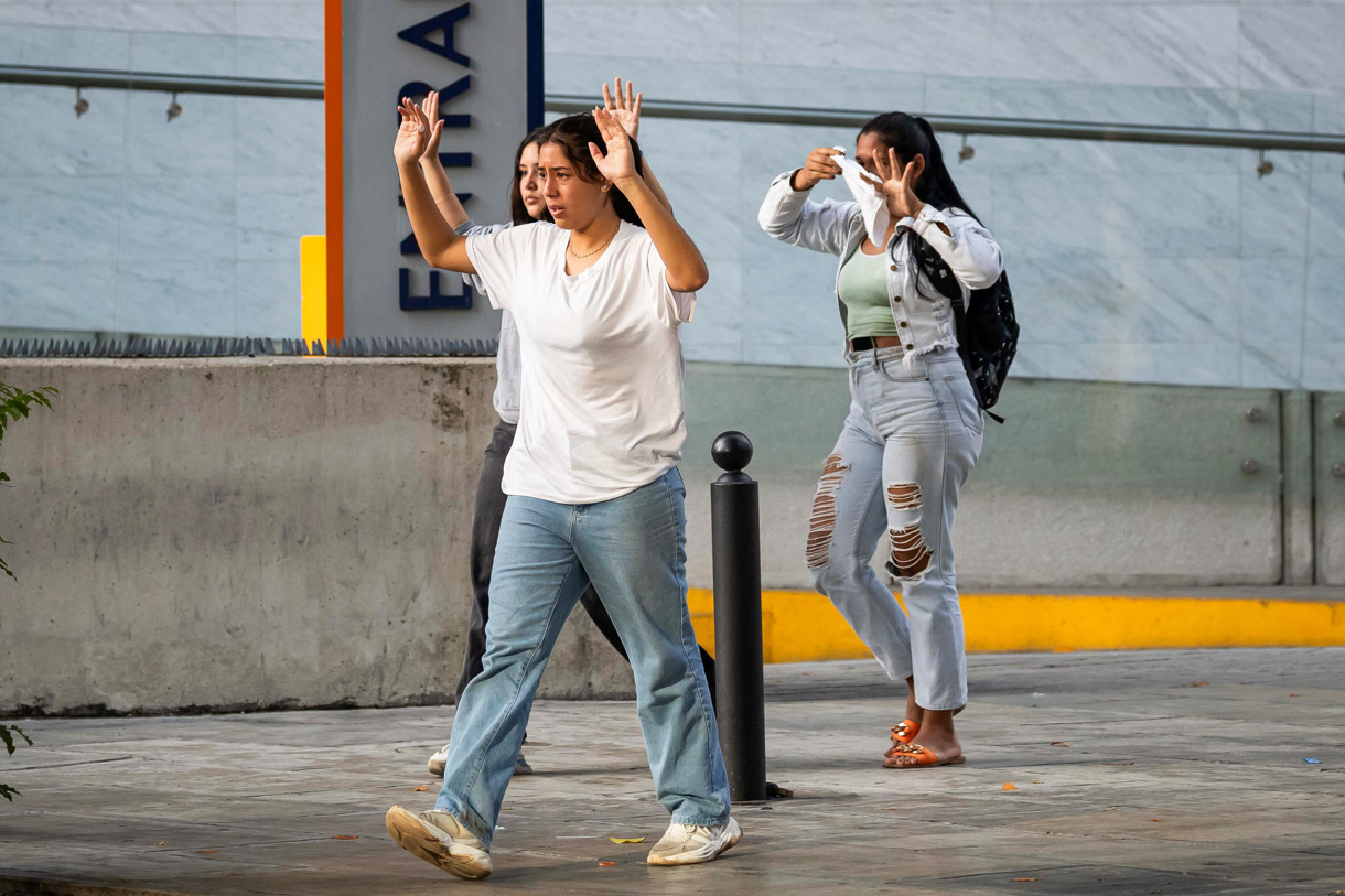 Tres jóvenes avanzan con las manos arriba para evitar ataque de integrantes de la Policía Nacional Bolivariana (PNB) y la Guardia Nacional Bolivariana (GNB) durante enfrentamientos con manifestantes opositores el lunes, durante una protesta contra de los resultados de las elecciones presidenciales en Caracas (Venezuela). (Fotografía de Ronald Peña R. de la agencia EFE)