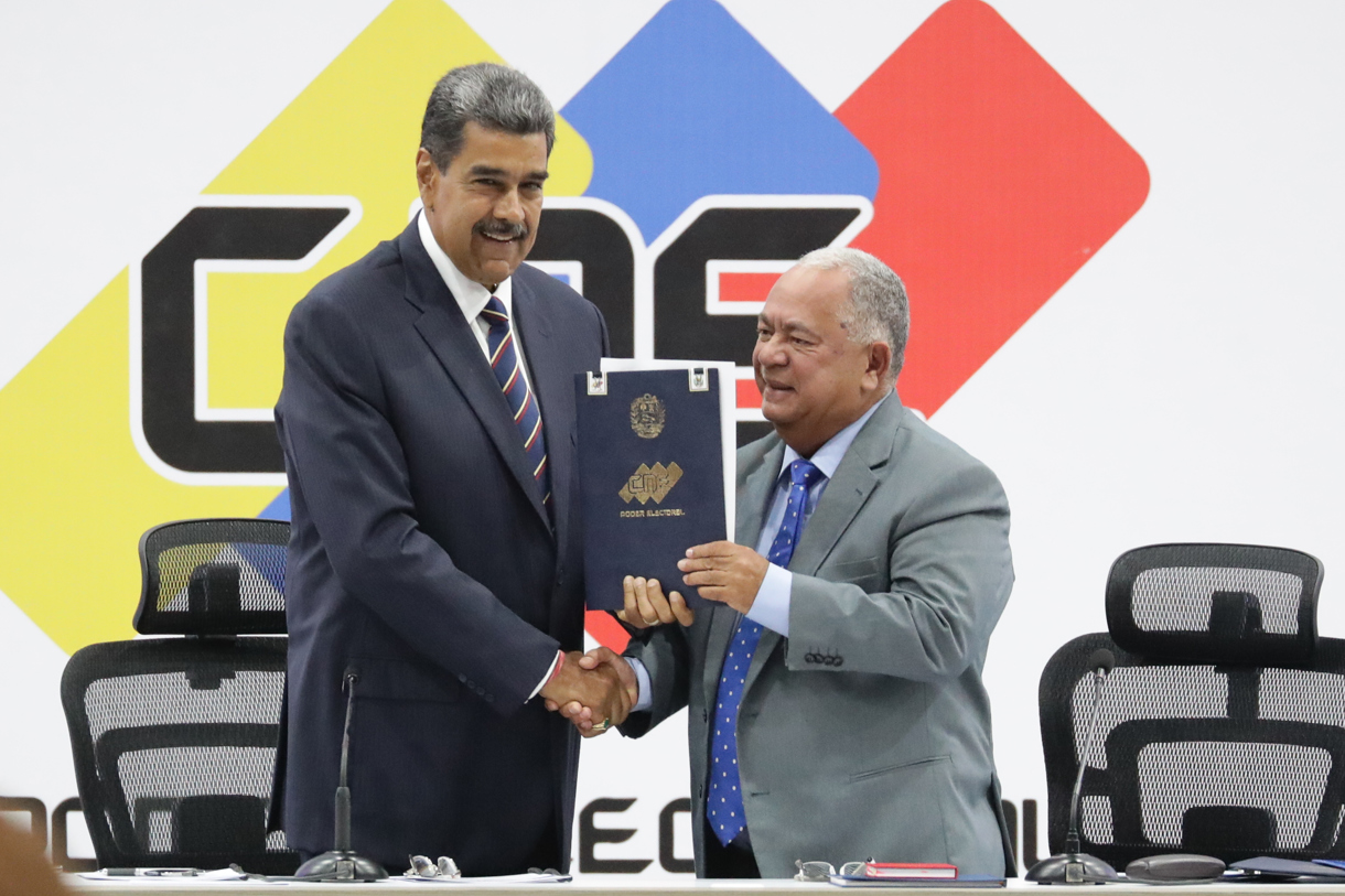 El presidente de Venezuela, Nicolás Maduro (i), y el presidente de Consejo Nacional Electoral (CNE), Elvis Amoroso, sostienen el acta de juramentación del presidente electo este lunes, en Caracas (Venezuela). (Fotografía de Ronald Peña R. de la agencia EFE)