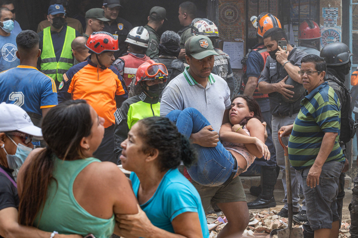 Un hombre carga a una mujer en la zona donde se derrumbó un edificio de 3 pisos este lunes, en el barrio Unión de Petare en Caracas (Venezuela). (Foto de Henry Chirinos de la agencia EFE)