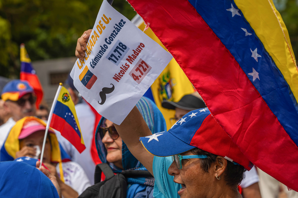 Manifestantes sostienen pancartas y banderas durante una protesta convocada por María Corina Machado este miércoles frente a la Basílica de nuestra señora de Chiquinquirá en Maracaibo (Venezuela). (Foto de Henry Chirinos de la agencia EFE)