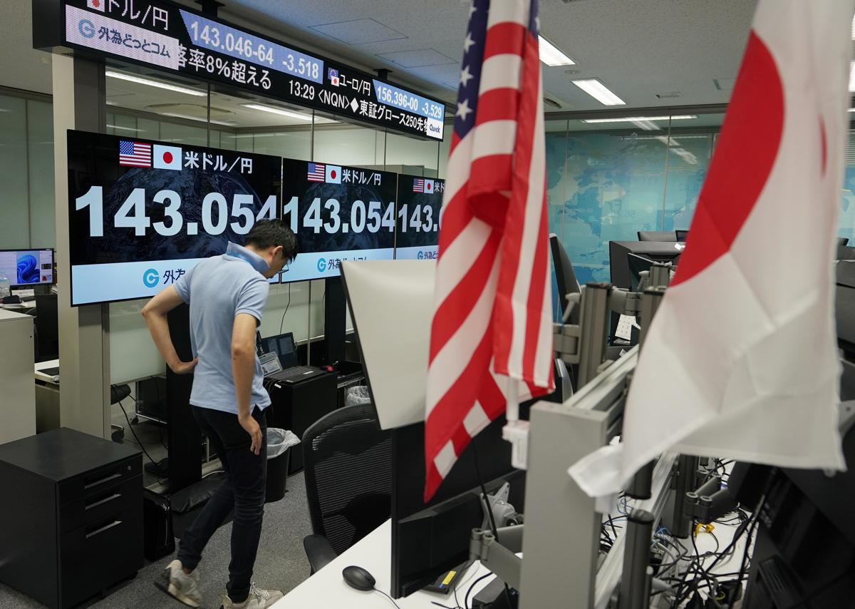 Un comerciante camina junto a monitores que muestran el tipo de cambio entre el yen japonés y el dólar estadounidense en Tokio, este lunes, cundo los mercados bursátiles sufrieron grandes desplomes. (Foto de Kimimasa Mayama de la agencia EFE/EPA)