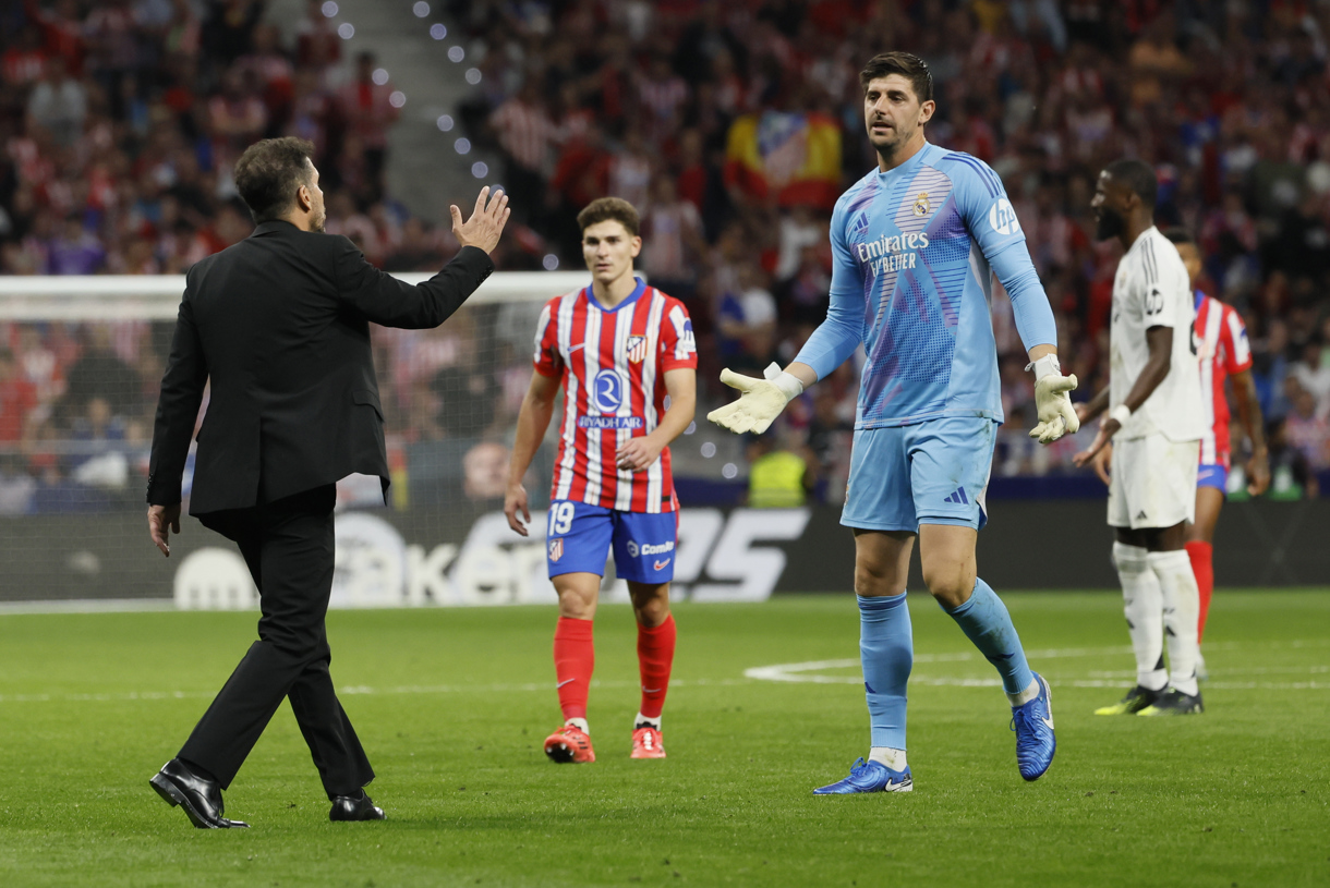 El portero del Real Madrid Thibaut Courtois (d) conversa con el entrenador del Atlético, Diego Simeone (i), durante el partido de la LaLiga EA Sports que Atlético de Madrid y Real Madrid que disputaron el domingo en el estadio Civitas Metropolitano. (Foto de Ballesteros de la agencia EFE)