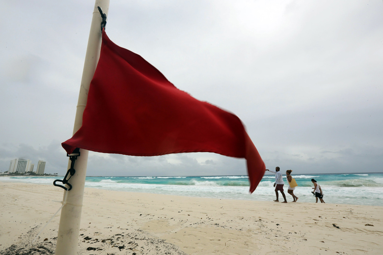 Turistas caminan por una playa con alto oleaje debido a la tormenta tropical Helen este martes, en el balneario de Cancún (México). (Foto de Alonso Cupul de la agencia EFE)