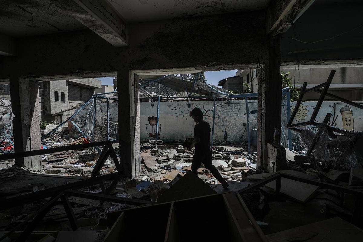 Un niño palestino desplazado internamente camina entre los escombros de la escuela administrada por la UNRWA, convertida en refugio, de Al-Jaouni. (Foto de Mohammed Saber de la agencia EFE/EPA)