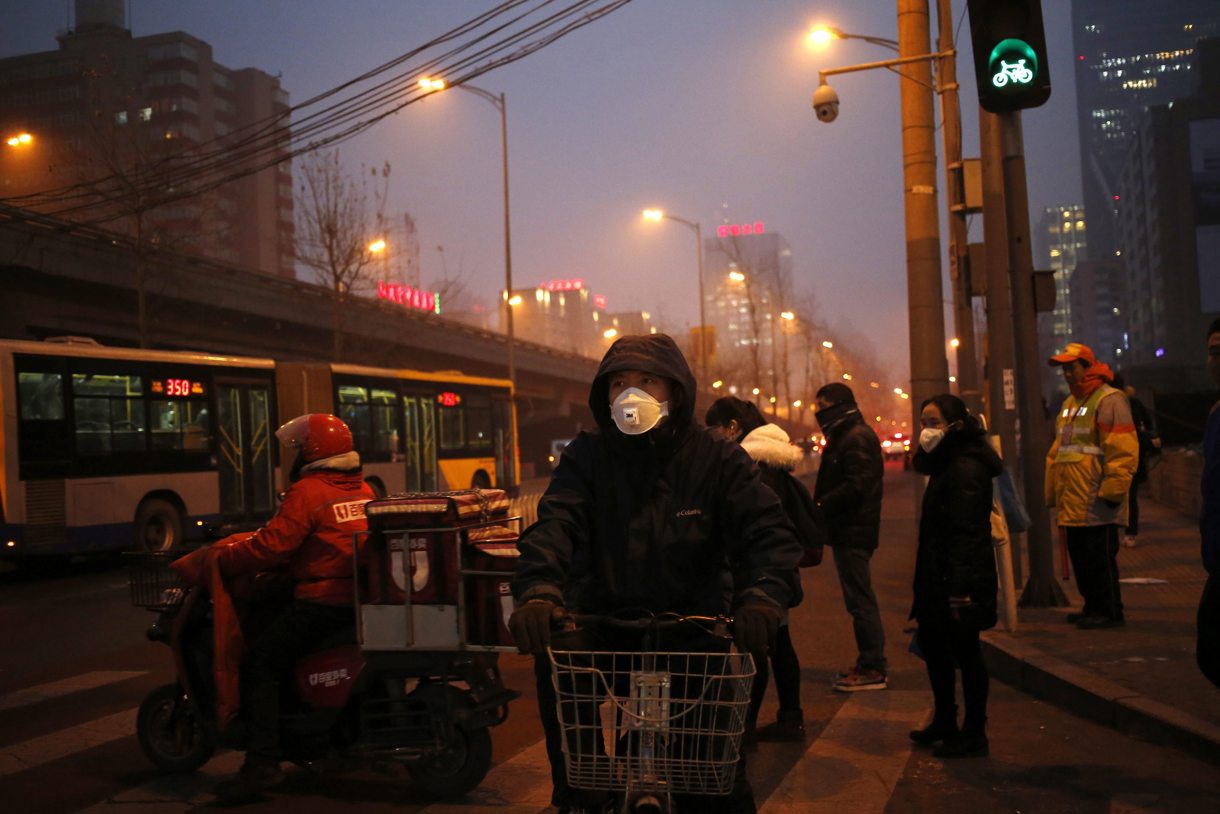 En la imagen de archivo, peatones utilizan mascarillas para protegerse de la contaminación en Pekín (China). (Foto de How Hwee Young de la agencia EFE)