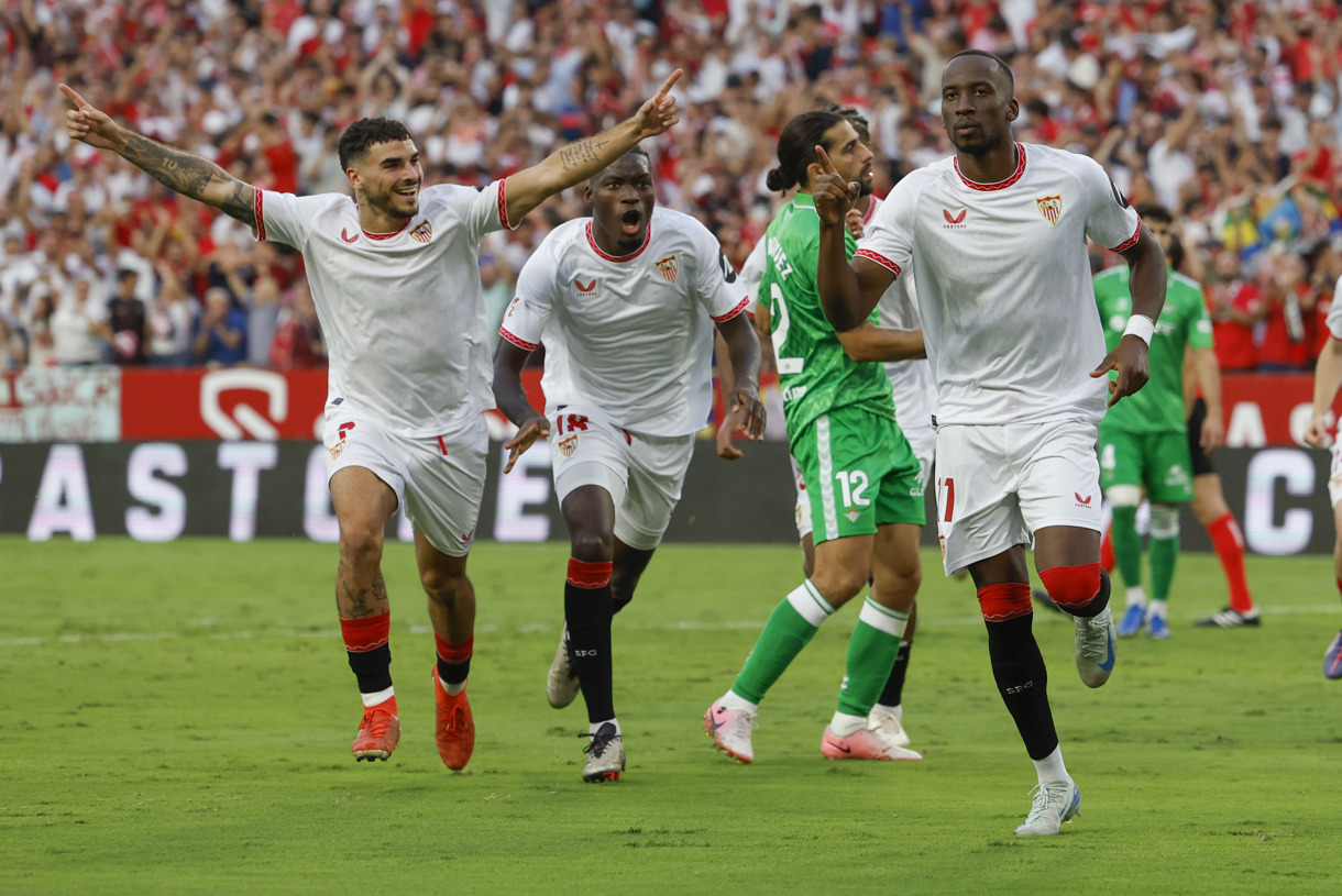 El centrocampista belga del Sevilla Dodi Lukebakio (i) celebra con sus compañeros su gol marcado de penalti durante el partido de la novena jornada de LaLiga que Sevilla FC y Real Betis disputaron en el estadio Ramón Sánchez-Pizjuán, en Sevilla. (Foto de Julio Muñoz de la agencia EFE)