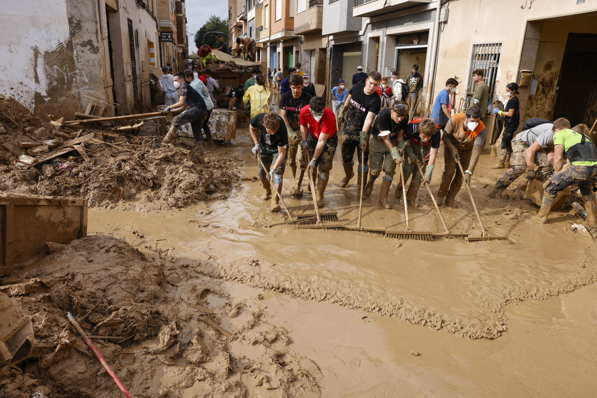 Voluntarios barren el lodo de una calle de Masanasa, Valencia, este jueves. (Foto de Ana Escobar de la agencia EFE)