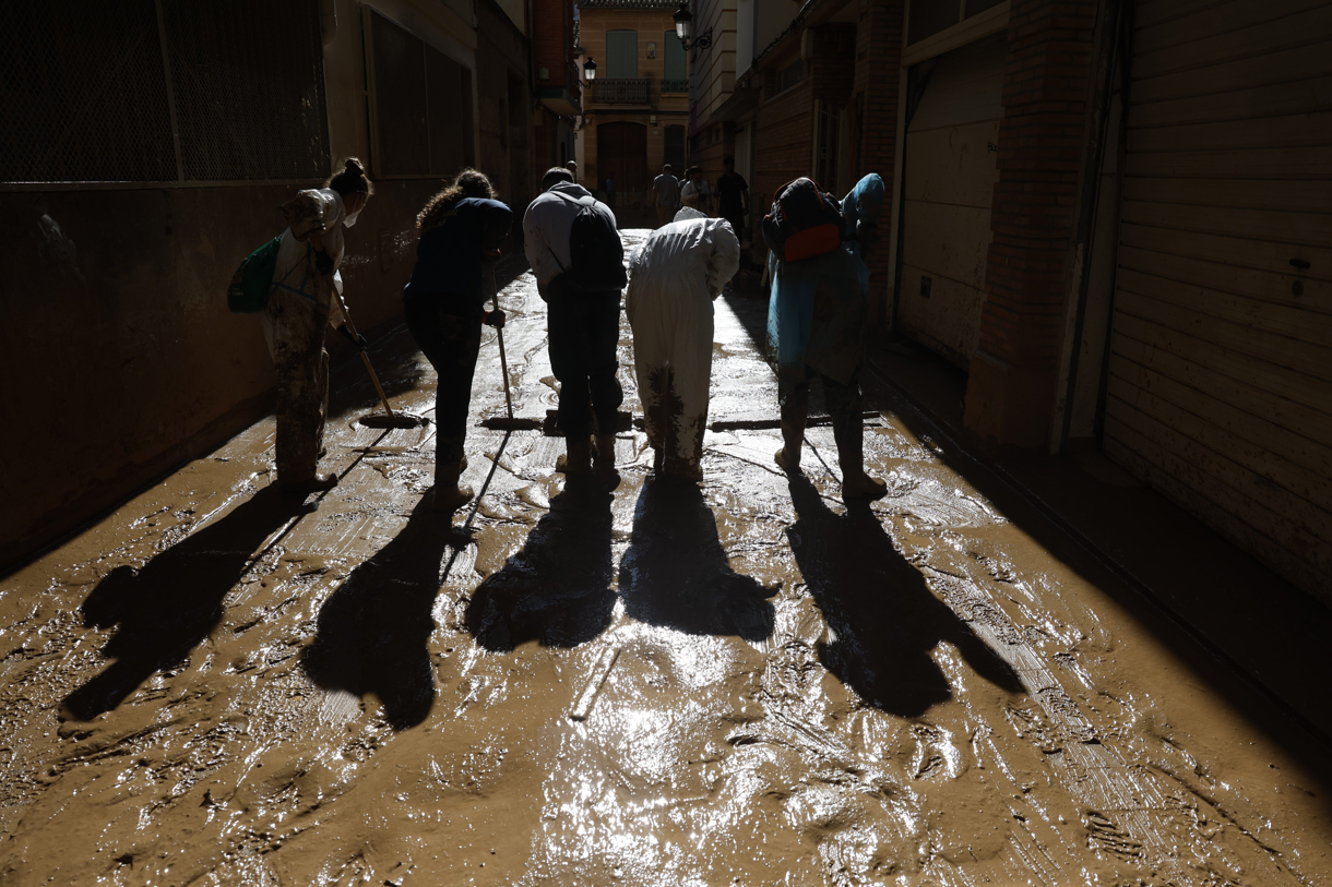 Voluntarios limpian este domingo el barro de una calle de la localidad española de Paiporta, una de las más perjudicadas por las lluvias torrenciales de la provincia mediterránea de Valencia. (Foto de Jorge Zapata de la agencia EFE)