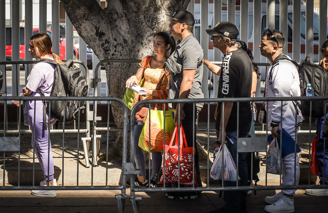 Migrantes hacen fila en la garita el Chaparral para cruzar la frontera hacia Estados Unidos en la ciudad de Tijuana, en Baja California (México). (Foto de archivo de Joebeth Terríquez de la agencia EFE)