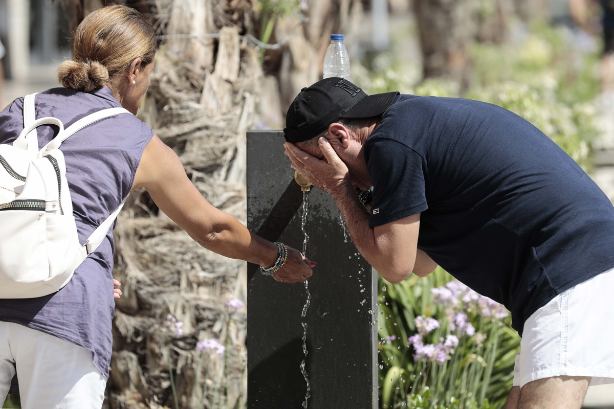 En la imagen de archivo, 2 personas se refrescan en una fuente del centro de Valencia, España. (Foto de Ana Escobar de la agencia EFE)