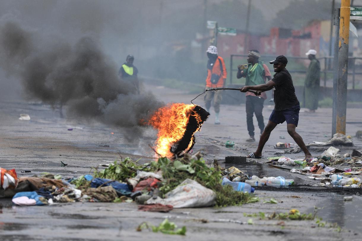 Un manifestante lleva un neumático en llamas durante una protesta en el día de la inauguración del nuevo parlamento, en Maputo, Mozambique, 13 de enero de 2025. (Foto de Luisa Nhantumbo de la agencia EFE/EPA)