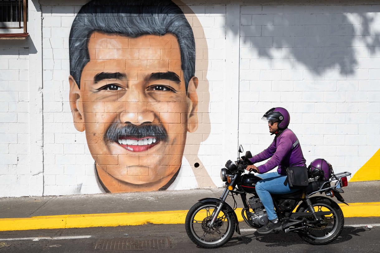 Un motociclista pasa frente a un mural del líder chavista Nicolás Maduro este martes, en Caracas (Venezuela). (Foto Ronald Peña R. de la agencia EFE)