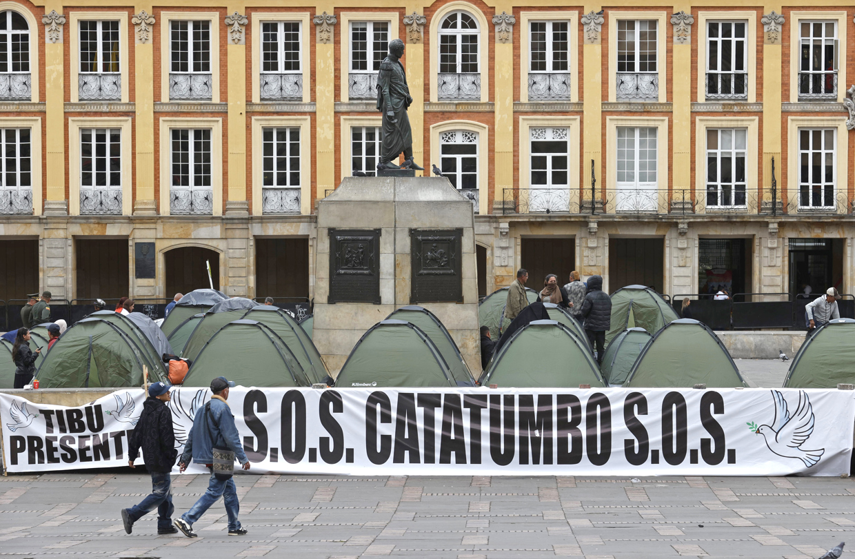 Fotografía de archivo que muestra personas caminando frente a un campamento de líderes campesinos de la región del Catatumbo, en la Plaza de Bolívar en Bogotá (Colombia). (Foto de Mauricio Dueñas Castañeda de la agencia EFE)