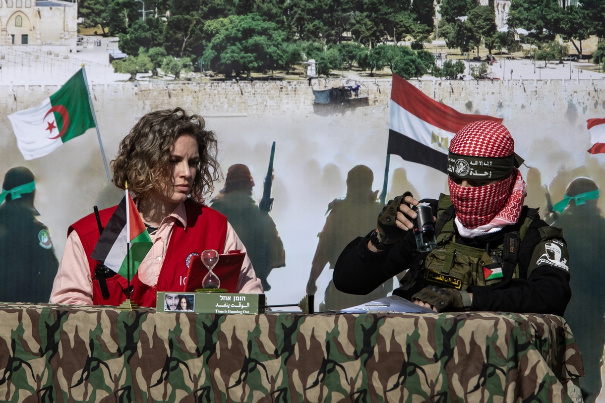 Fotografía del pasado sábado de una representante de la Cruz Roja y un combatiente palestino de las Brigadas Izz ad-Din al-Qassam de Hamas durante la liberación de 3 rehenes israelíes en Khan Yunis, al sur de la Franja de Gaza. (Foto de Haitham Imad de la agencia EFE/EPA)