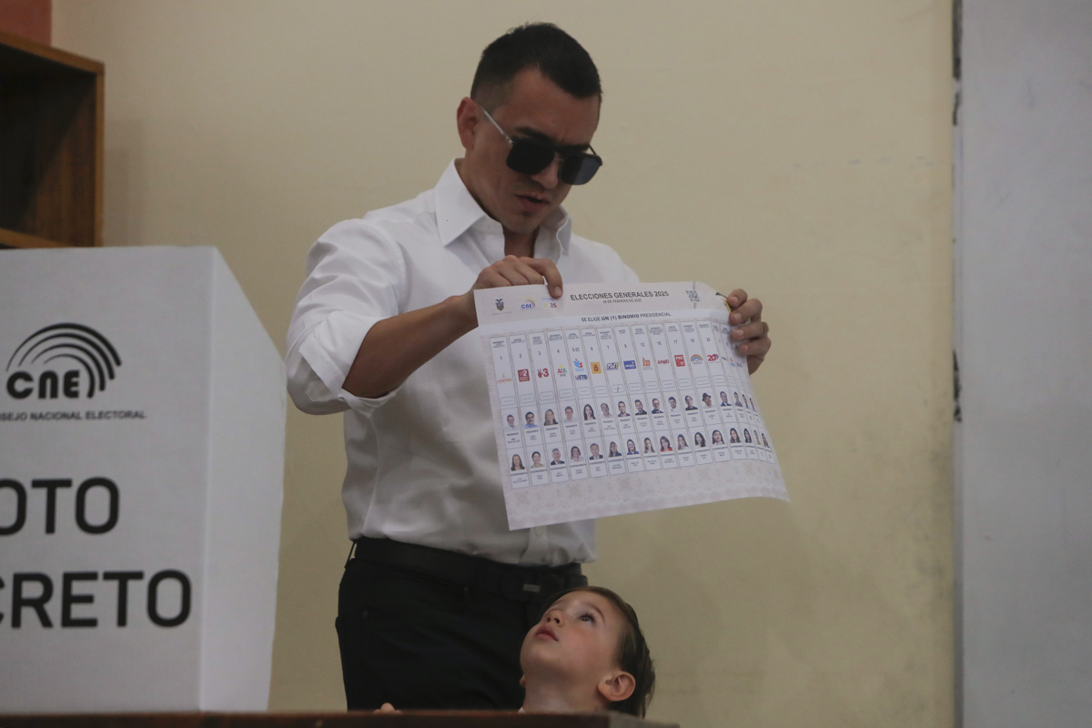 El presidente de Ecuador, Daniel Noboa, muestra su voto acompañado de su hijo Álvaro este domingo, en un puesto de votación en Olón (Ecuador). (Foto de Carlos Durán Araújo de la agencia EFE)
