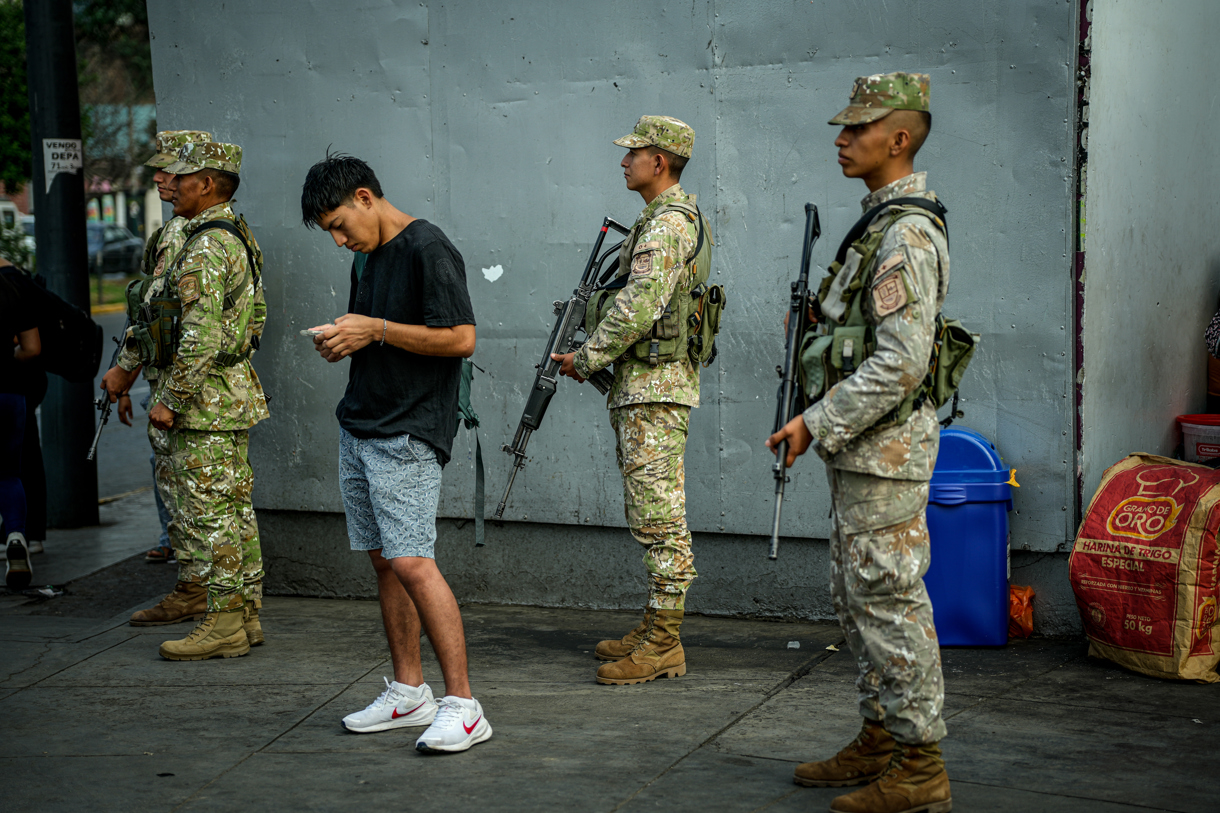 Un hombre mira su celular mientras integrantes de las Fuerzas Armadas de Perú custodian las calles este martes, en Lima (Perú). (Foto de John Reyes Mejía de la agencia EFE)