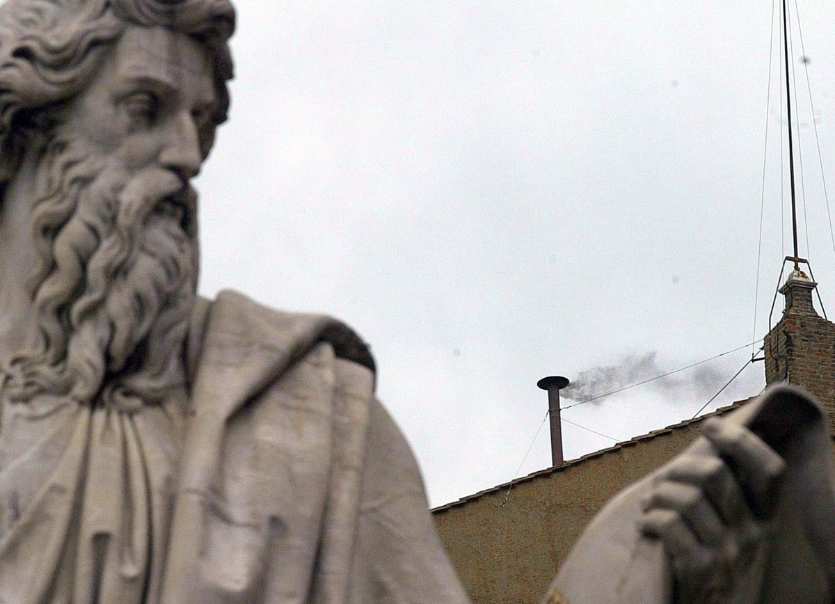 Imagen de archivo del humo negro que sale de la chimenea del tejado de la Capilla Sixtina tras una de las estatuas de la Plaza de San Pedro del Vaticano. (Foto de Danilo Schiavella de la agencia EFE)